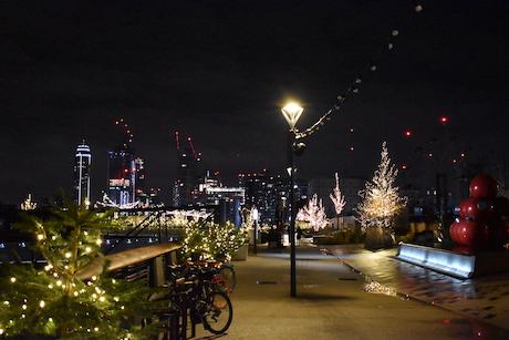 Christmassy lights next to a lamp at night with Nine elms buildings lit up in the background